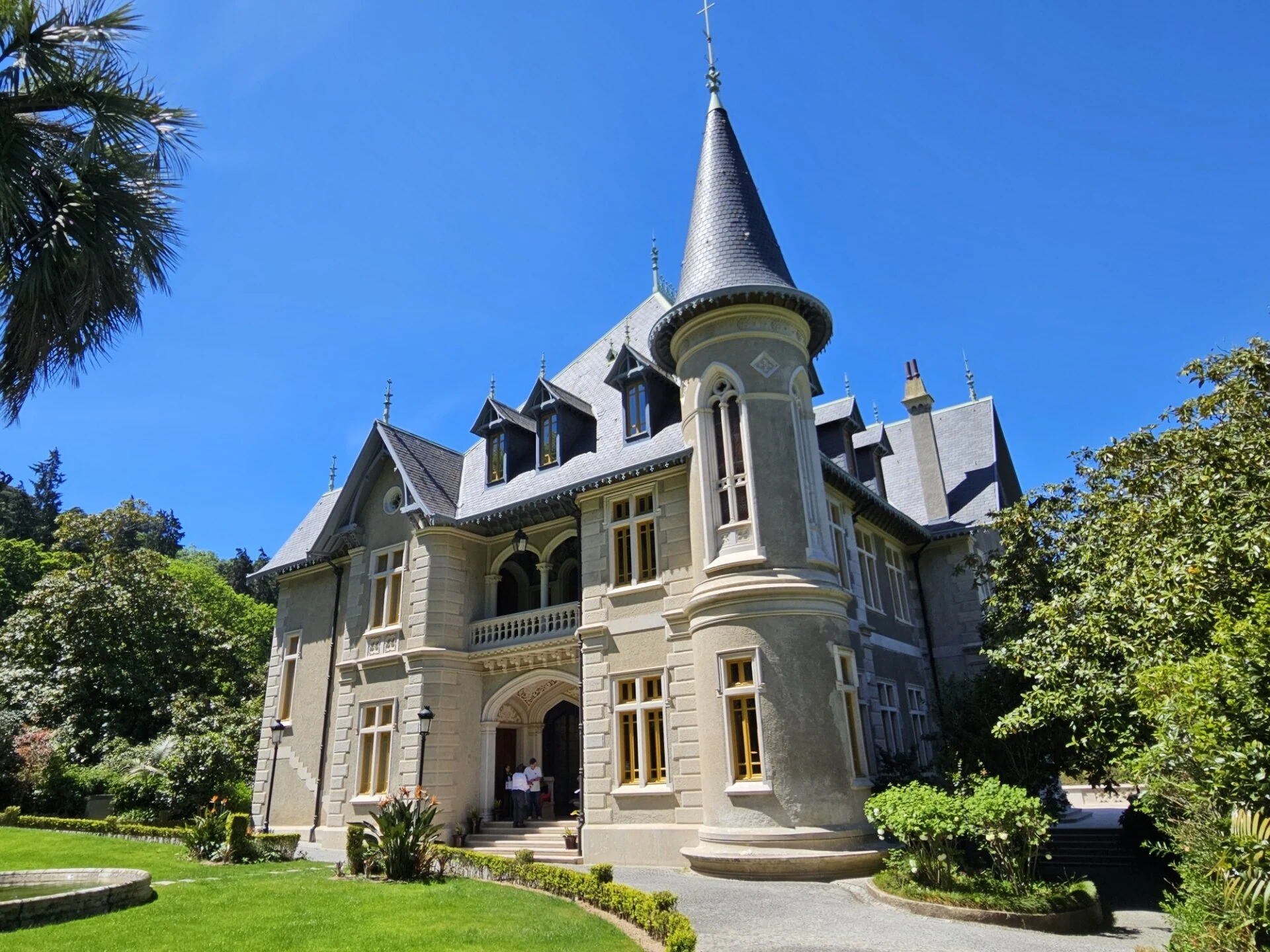 Biester Palace's pointed tower, decorated facade and garden on a sunny day